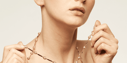 Collar compuesto por una fina cadena bañada en oro, adornada con cuentas de color perla envueltas en una delicada red metálica y un gran colgante con nácar.