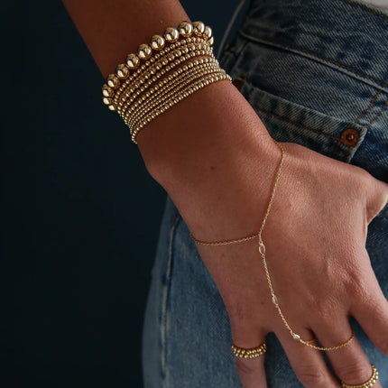 Hand chain en gold filled de 14k con tres topacios blancos y diseño delicado unido entre muñeca y dedo